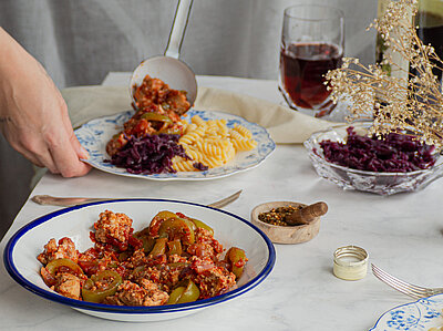 Gulasch Tofu-Gulasch mit Nudeln auf Tellern auf einer Tischdecke mit Tischdekoration.