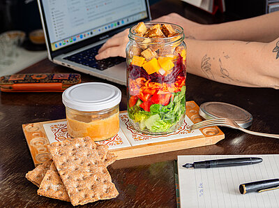 Salat aus dem Glas Tofuwürfel mit rote Bete Würfel, Kichererbsen und Salat an Reis in einer Schüssel mit Tischdekoration.