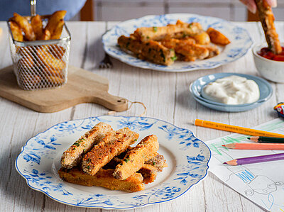 Räuchertofu-Sticks Panierte Tofu-Sticks auf Tellern mit Dip auf einem Tisch mit Dekoration.
