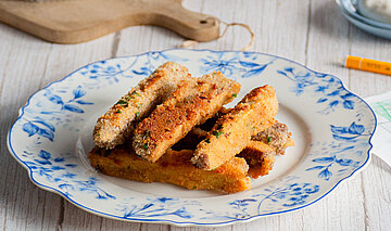 Räuchertofu-Sticks Panierte Tofu-Sticks auf Tellern mit Dip auf einem Tisch mit Dekoration.