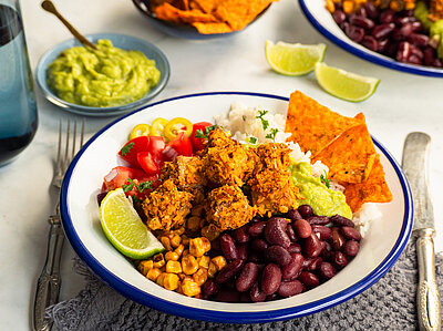 Crunchy Tortilla-Tofu Panierte Tofu-Würfel mit Gemüse und Dip auf einem Teller und Tischdekoration.