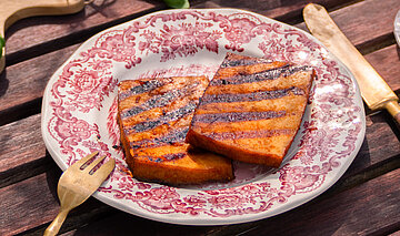 BBQ-Tofu-Marinade Tisch mit Tellern von Tofu, Nudeln, Oliven, Tomaten und Dekoration.