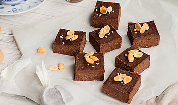 Erdnuss Tofu Fudge Erdnuss Brownies auf einer Tischdecke mit Dekoration.
