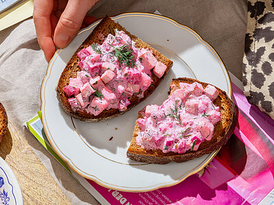 Heringssalat Roter Tofu-Heringssalat auf Brotscheiben auf einem Teller mit Tischdekoration.