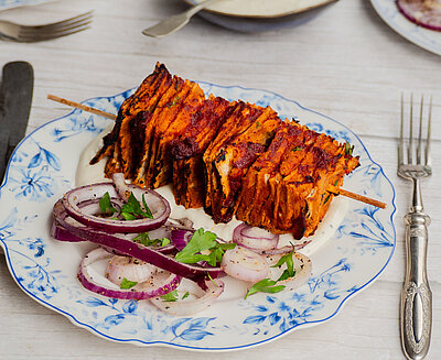 Tofu-Kebab-Spieße Tofu-Spieß mit Zwiebeln und Kräutern auf einem Teller mit Dip und Tischdekoration.