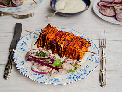 Tofu-Kebab-Spieße Tofu-Spieß mit Zwiebeln und Kräutern auf einem Teller mit Dip und Tischdekoration.