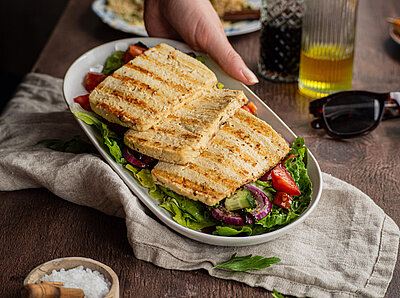 Tofu wie Halloumi 3 gegrillte Tofuscheiben auf Salat in einer Schüssel mit Tischdekoration.