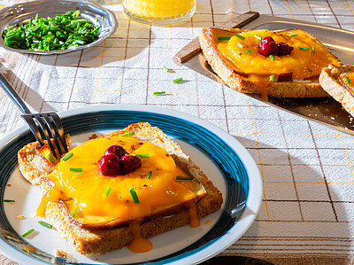 Toast Hawaii Scheiben Toast, jeweil mit einer Scheibe Tofu, Ananas, Käse und Kirschen belegt mit Tischdekoration.