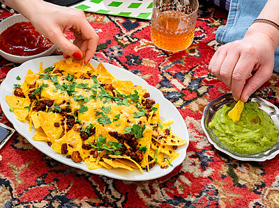 Loaded Nachos Nachos mit Garnitur sowie Guacomole und Dekoration.
